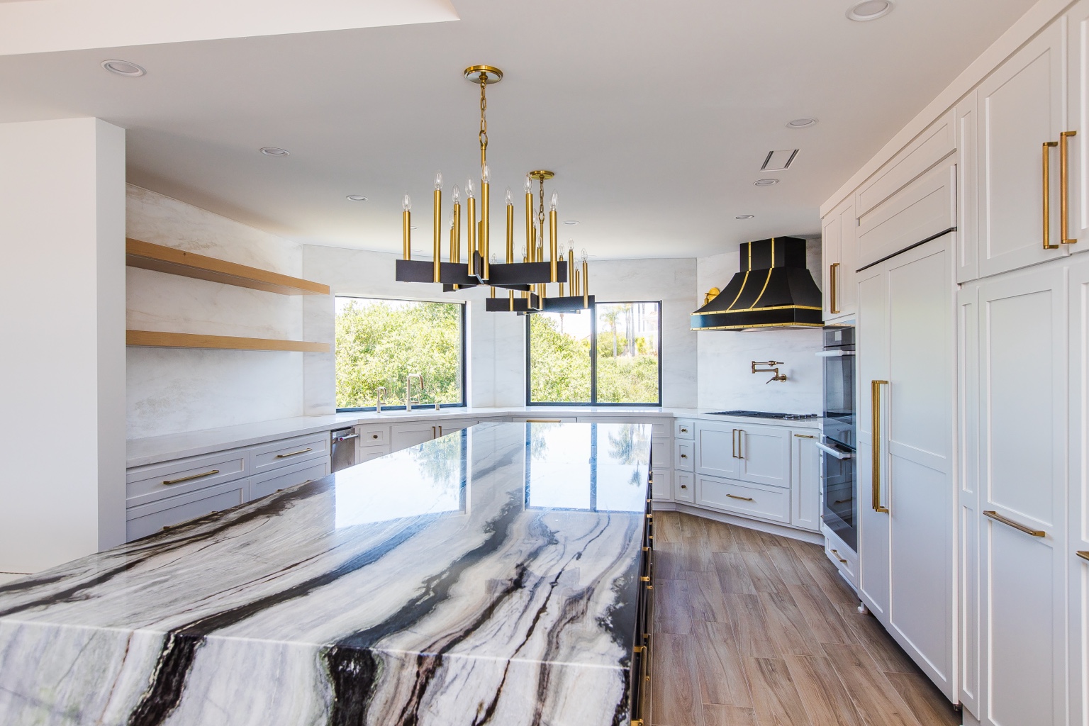 White custom kitchen cabinetry, brass details and a dark island