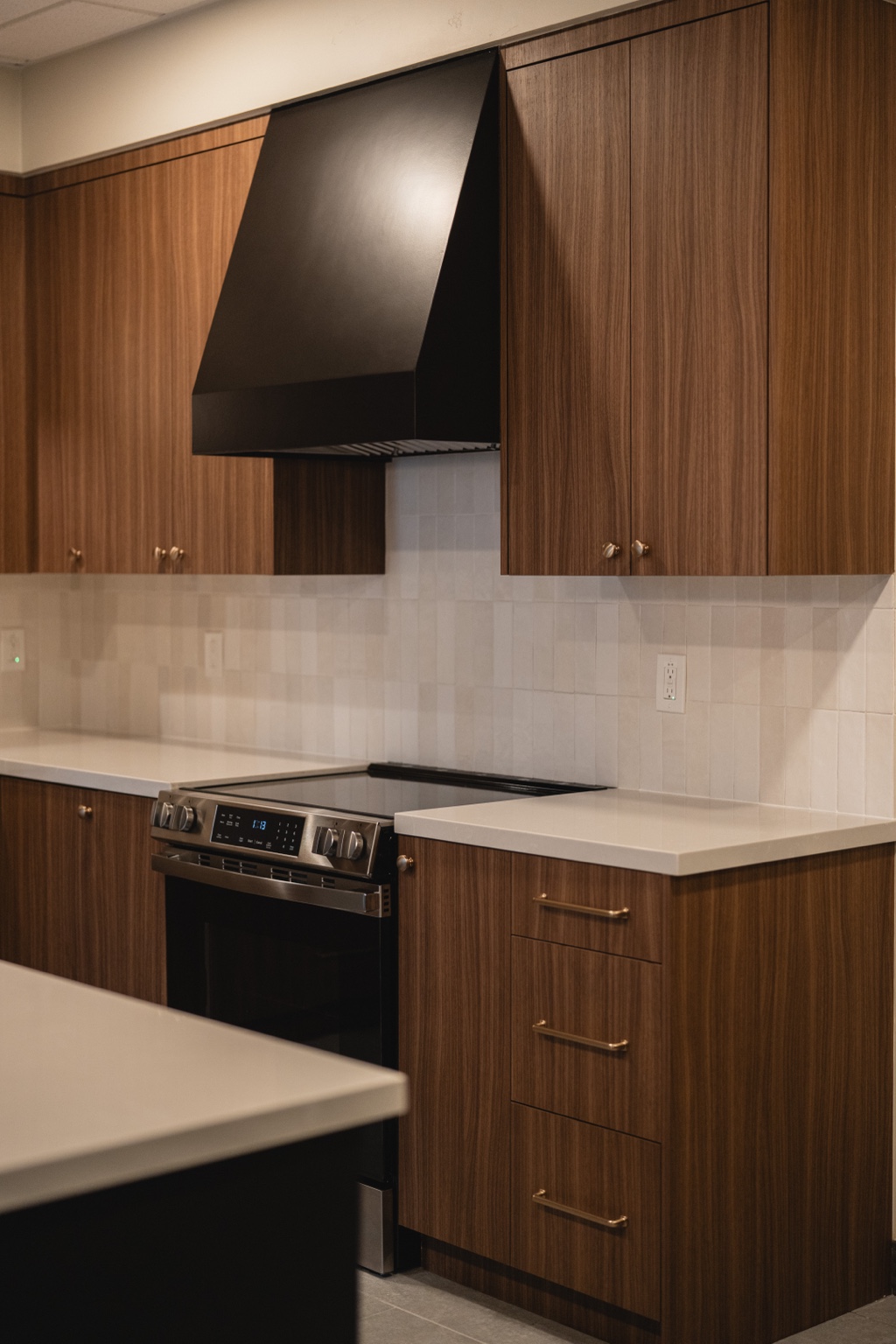Woodgrain cabinetry and brass hardware around a black range hood